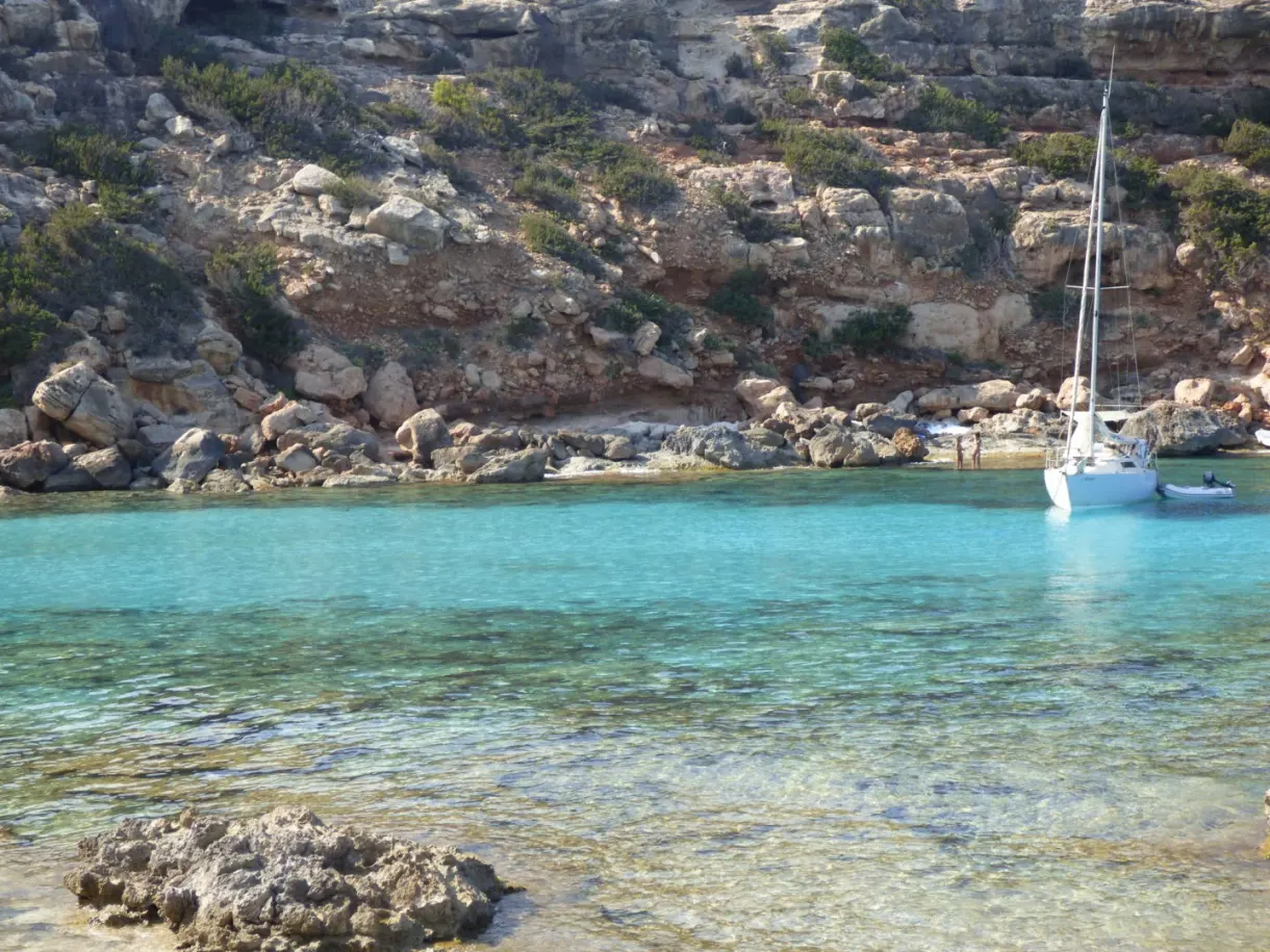 Sailing boat anchored in an inlet with rocky walls