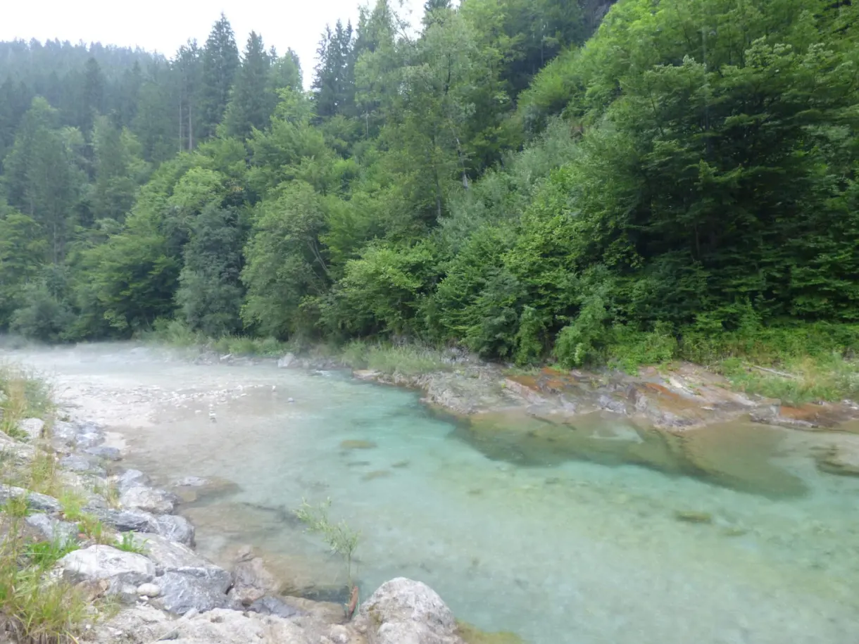 Turquoise river flowing between pebble banks