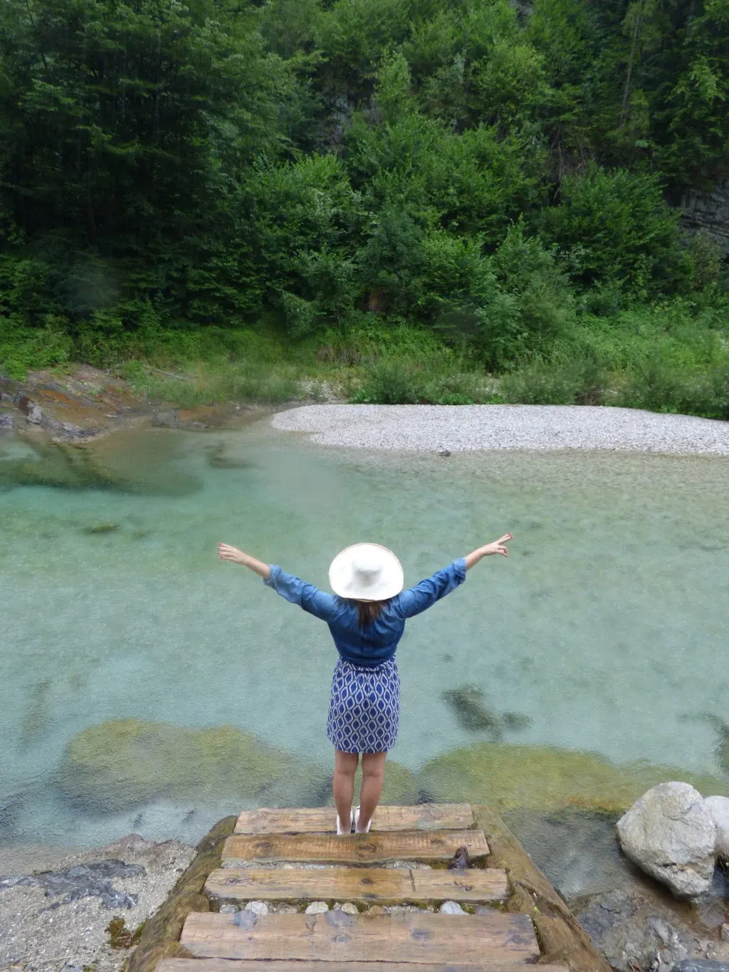 Arms open on a wooden pontoon above the clear water