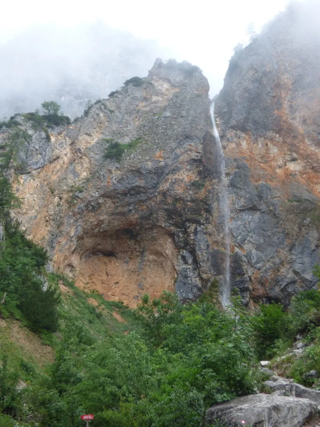 Waterfall bursting from a high ochre cliff