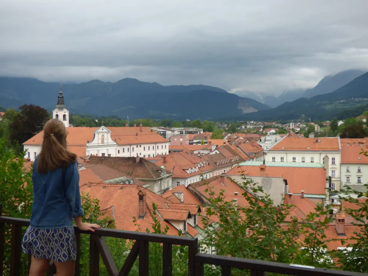 Leaning on a railing above the tiled rooftops