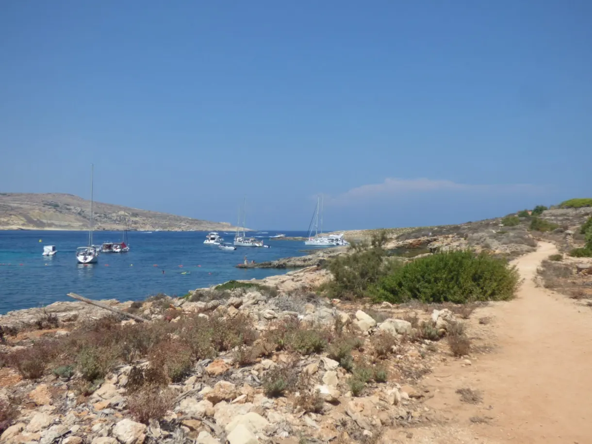 Sailing boats at anchor in front of a rocky point