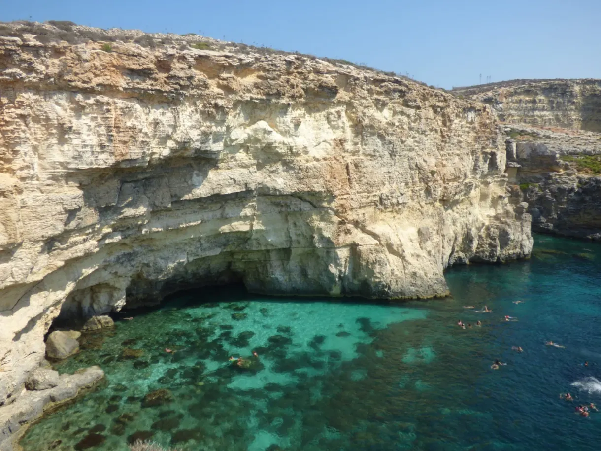 Cliff hollowed with caves above the clear water
