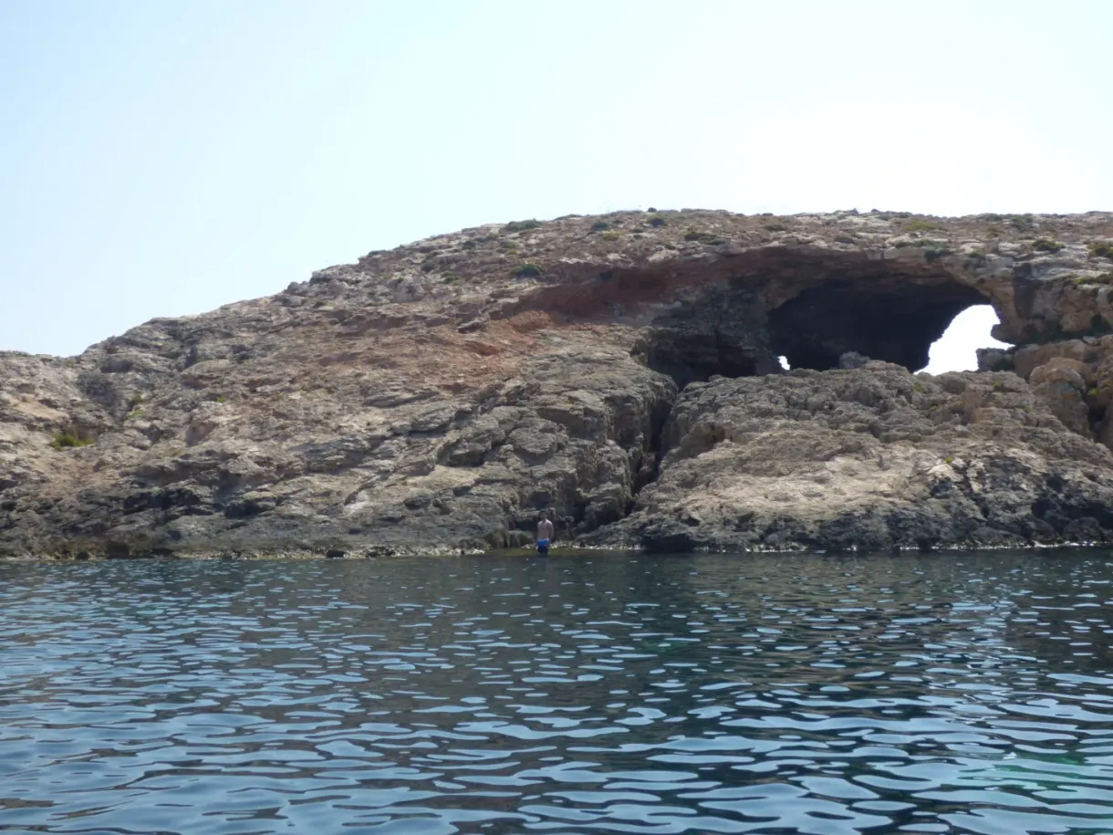 Natural arch pierced through the rock at water level