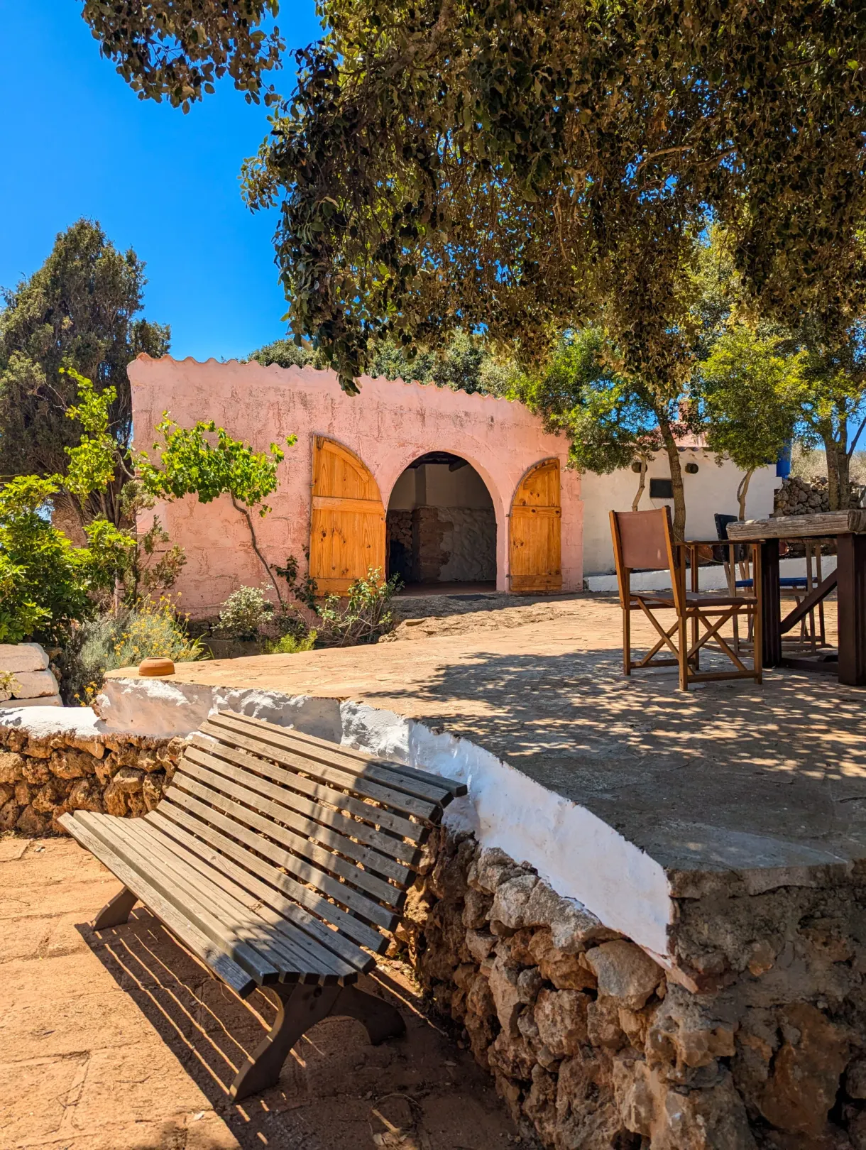 Shaded courtyard, wooden bench against a pink wall