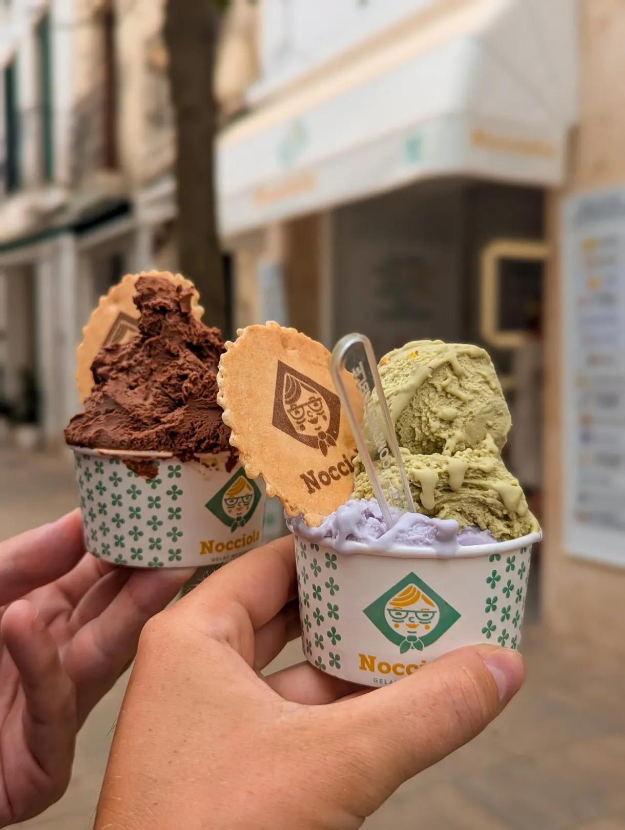 Two tubs of ice cream topped with a round wafer