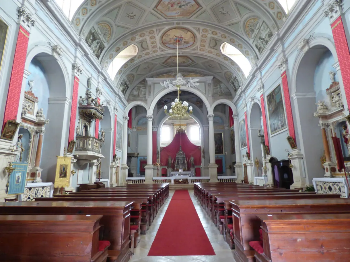 Baroque nave with red carpet and wooden pews in a church in Buje