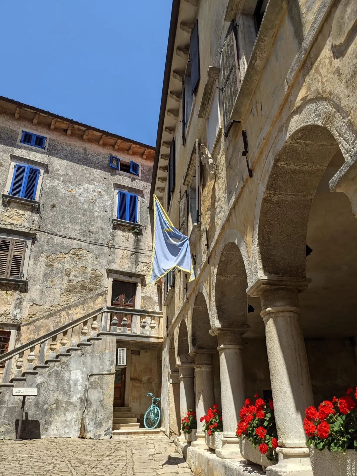 Arcaded loggia and stone staircase filled with geraniums in Grožnjan