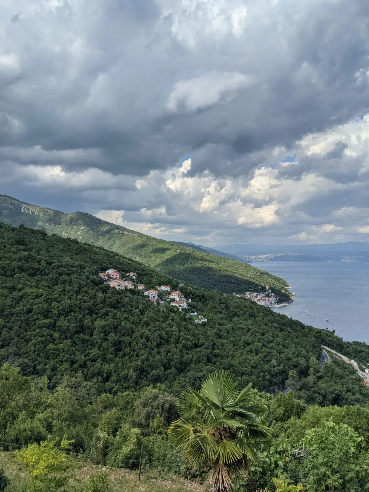 Green slope running down to the sea under heavy clouds, Mošćenice