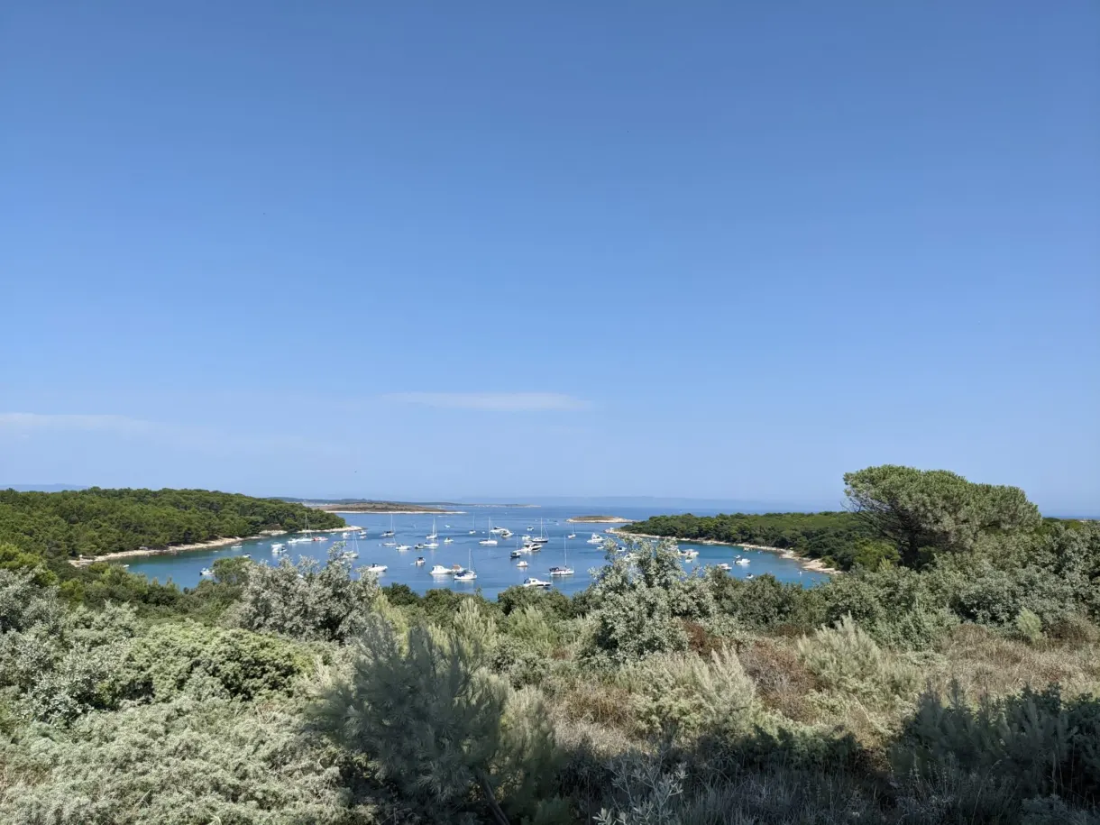 Boats at anchor in a bay lined with scrubland, Kamenjak
