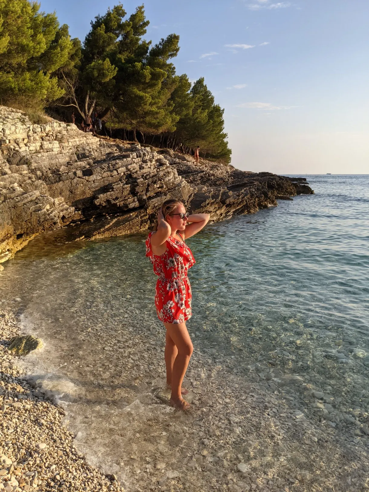 Woman in a flowered dress on a pebble beach in Kamenjak