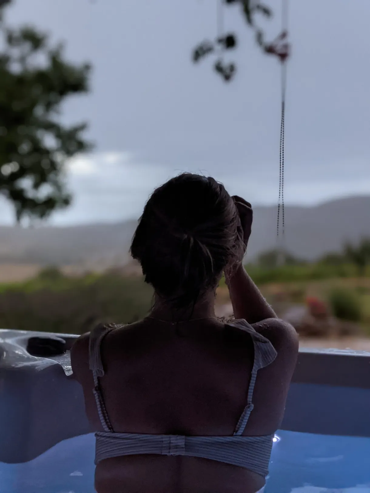 Woman seen from behind in the hot tub looking at the hills