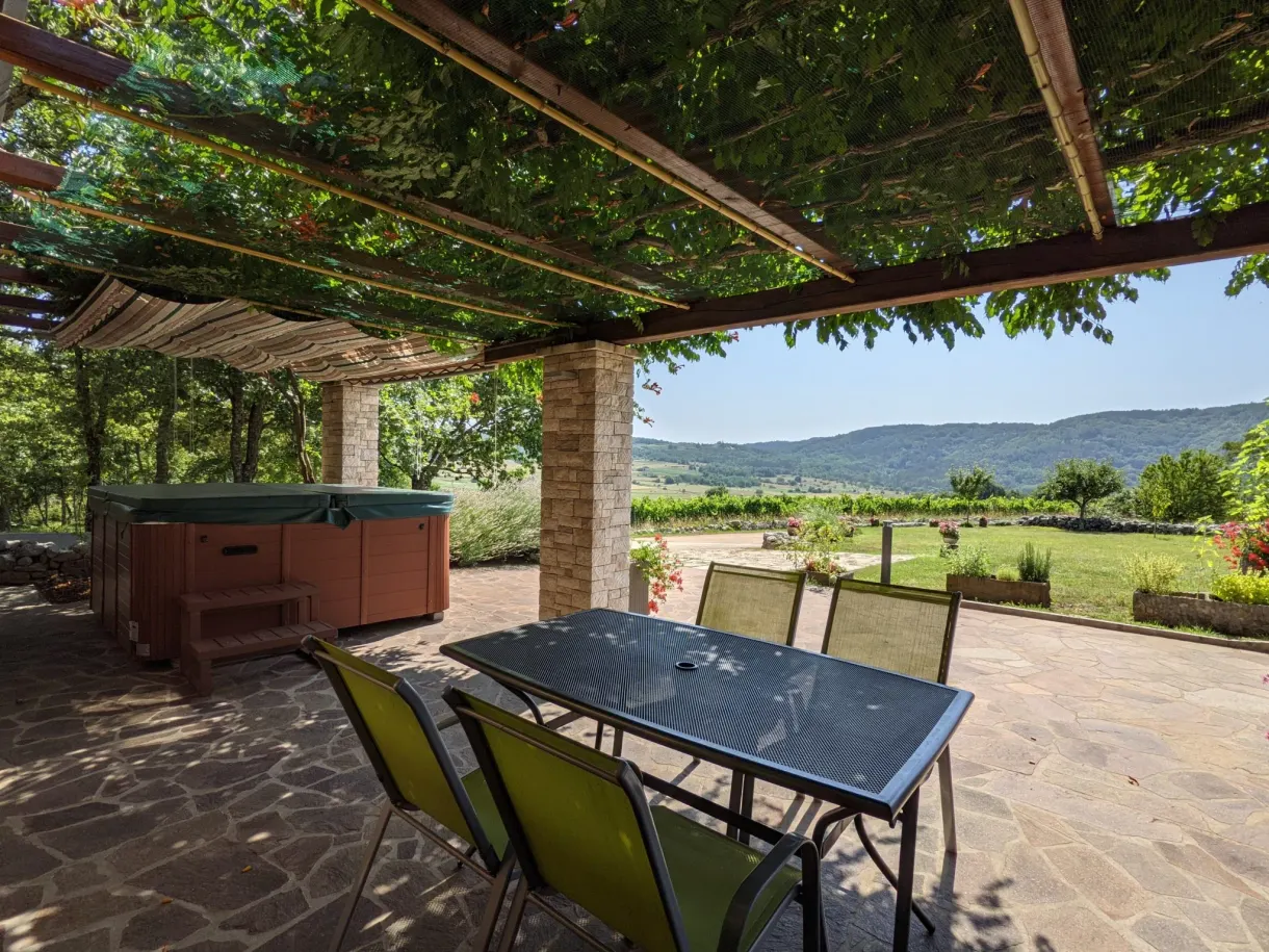 Table and chairs under the pergola of the terrace, hot tub at the back