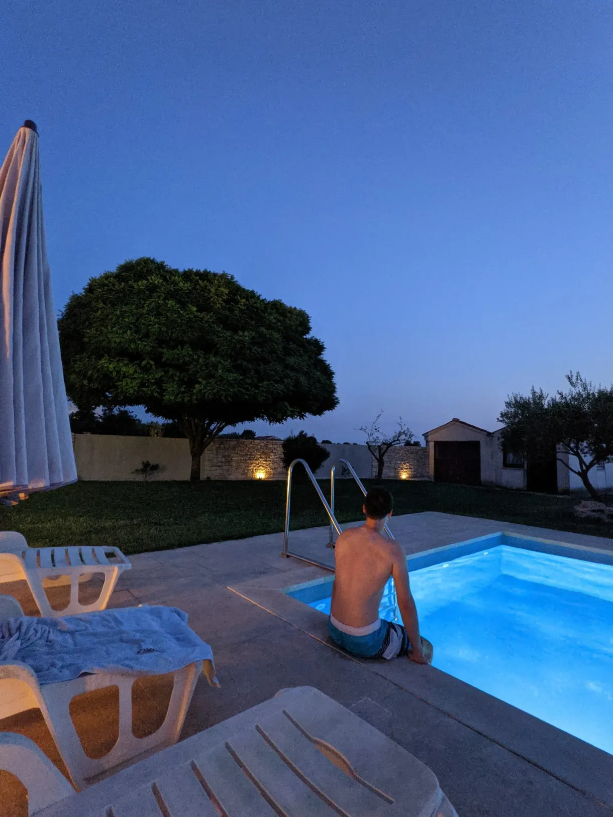 Pool lit up after nightfall under a large tree