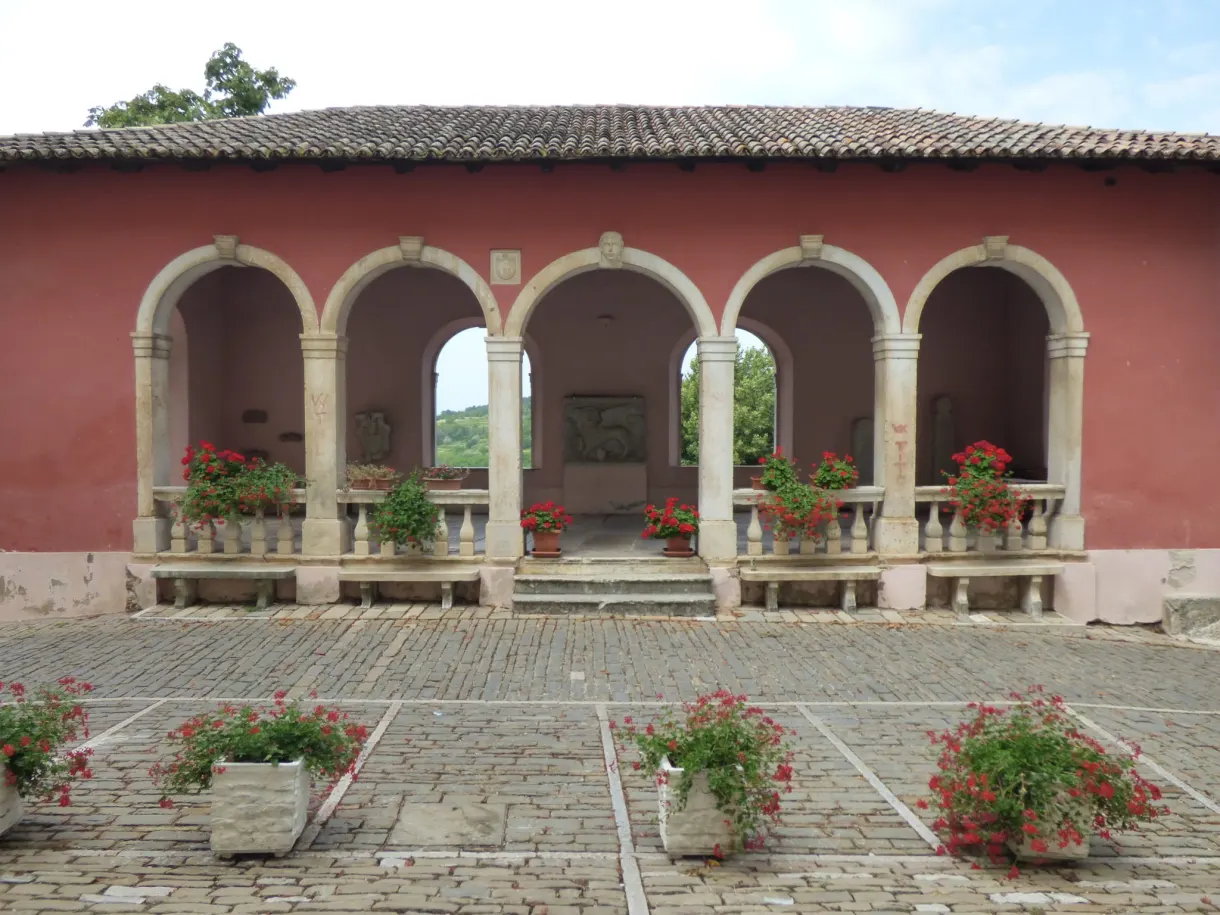 Pink arcaded loggia and pots of geraniums on a square in Oprtalj