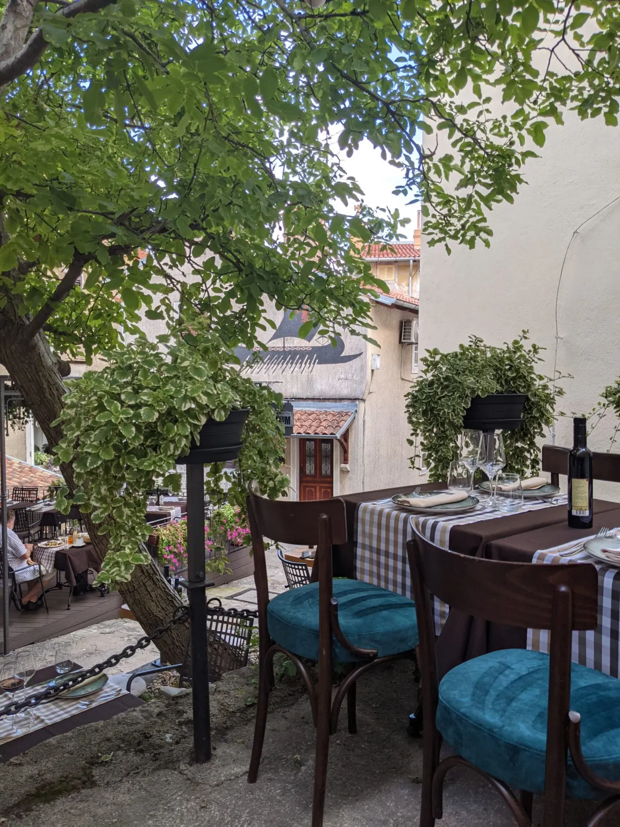 Restaurant terrace with turquoise chairs overlooking the village roofs