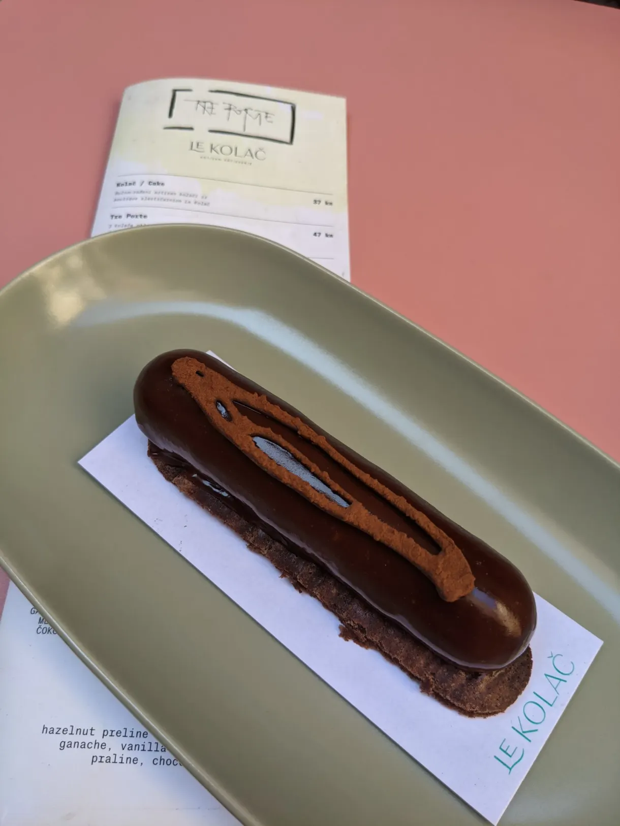 Chocolate eclair on a green tray next to the dessert menu