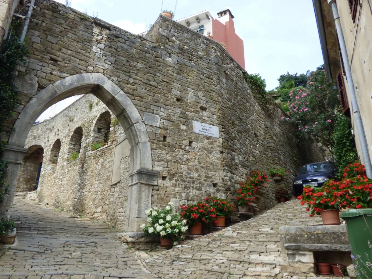 Large gothic arch of the town gate of Motovun, lined with geraniums