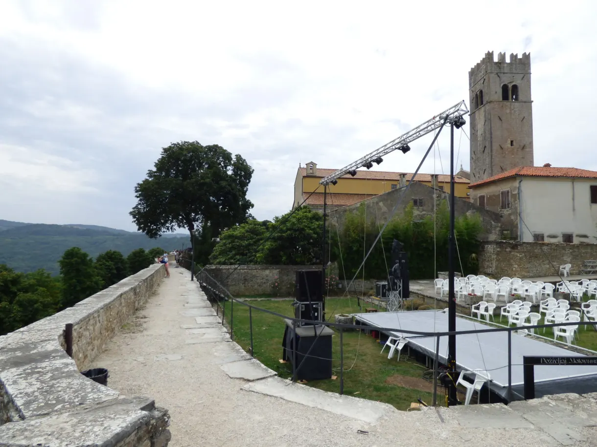 Stage and rows of white chairs set up at the foot of the Motovun tower