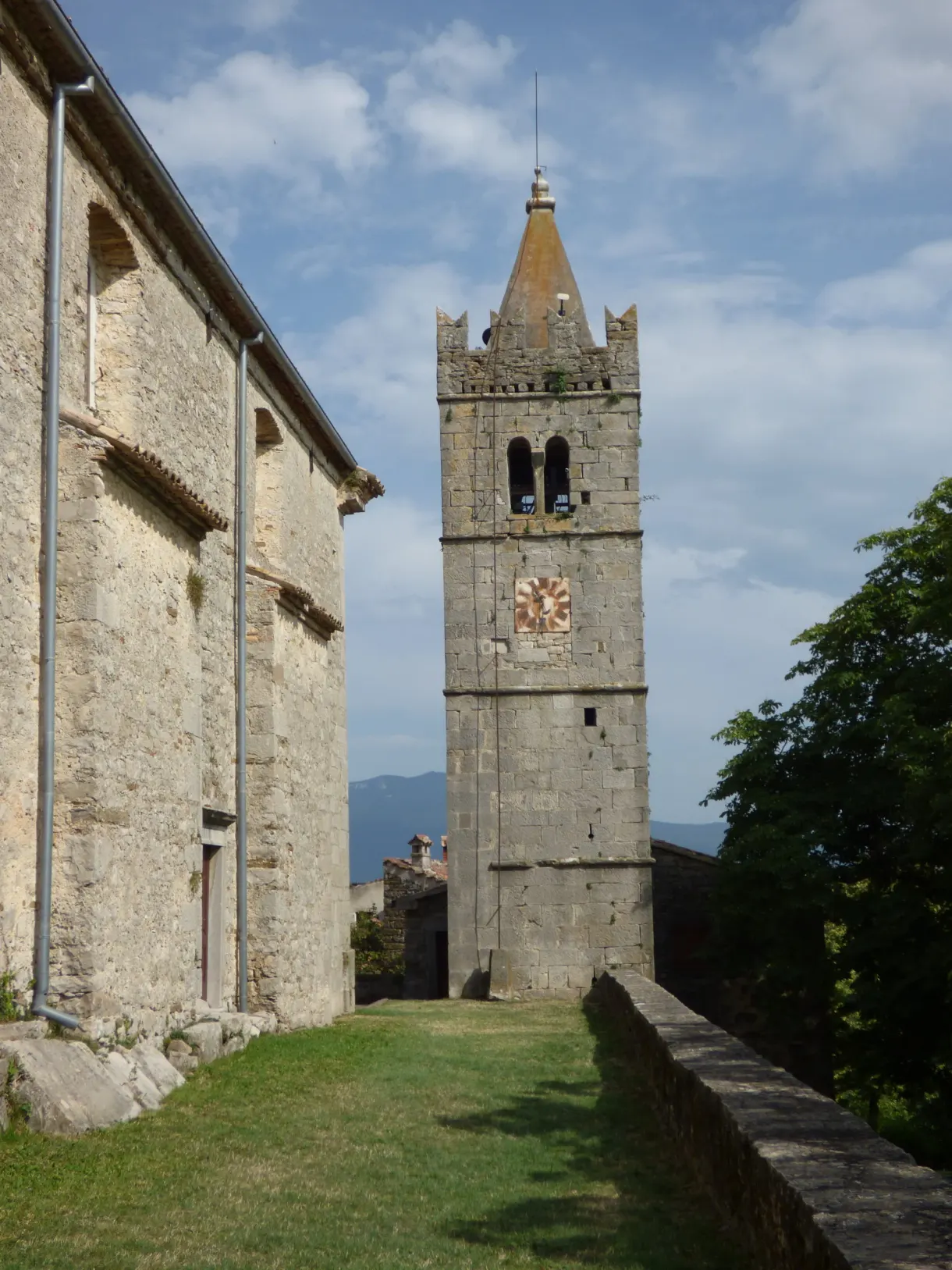 Stone church and clock tower of Hum on close-cropped grass