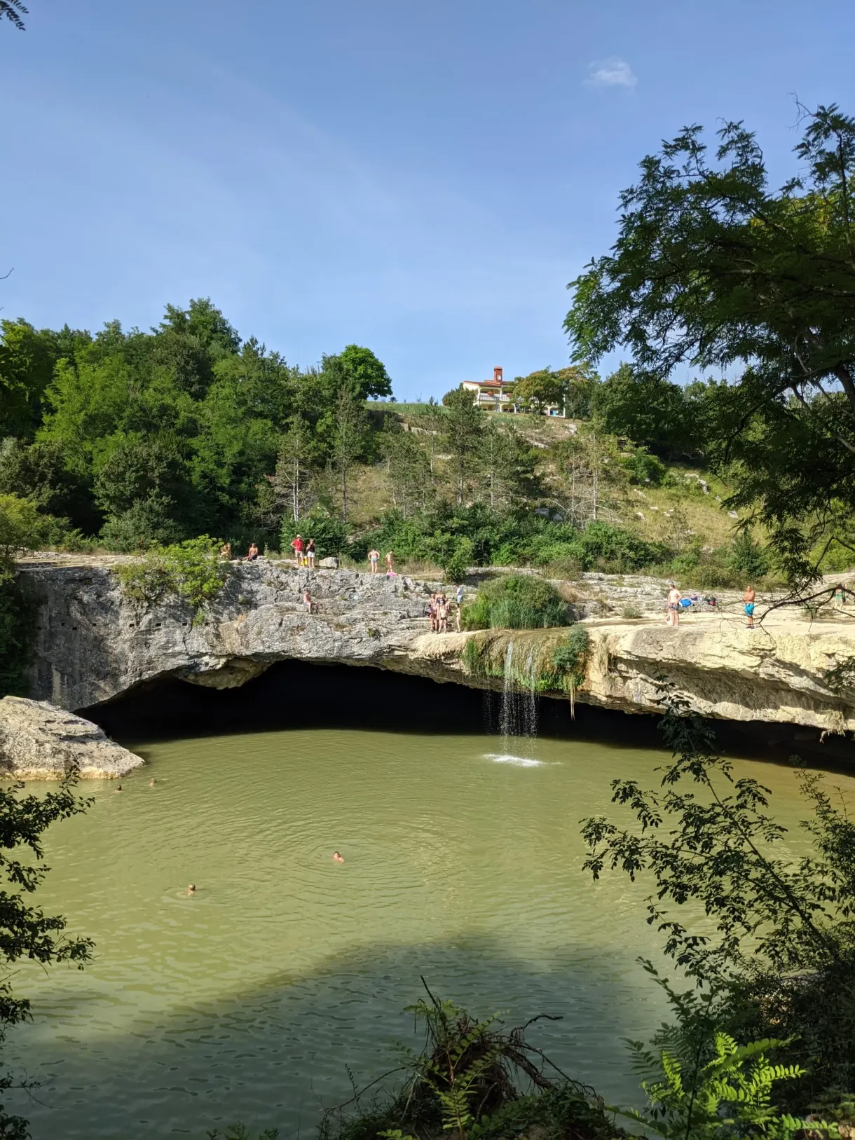 Green water and waterfall at the bottom of the cave of the Pazin chasm