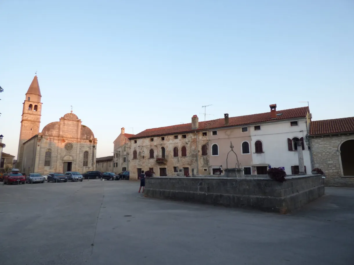 Church with a pink dome and bell tower on the main square of Svetvinčenat