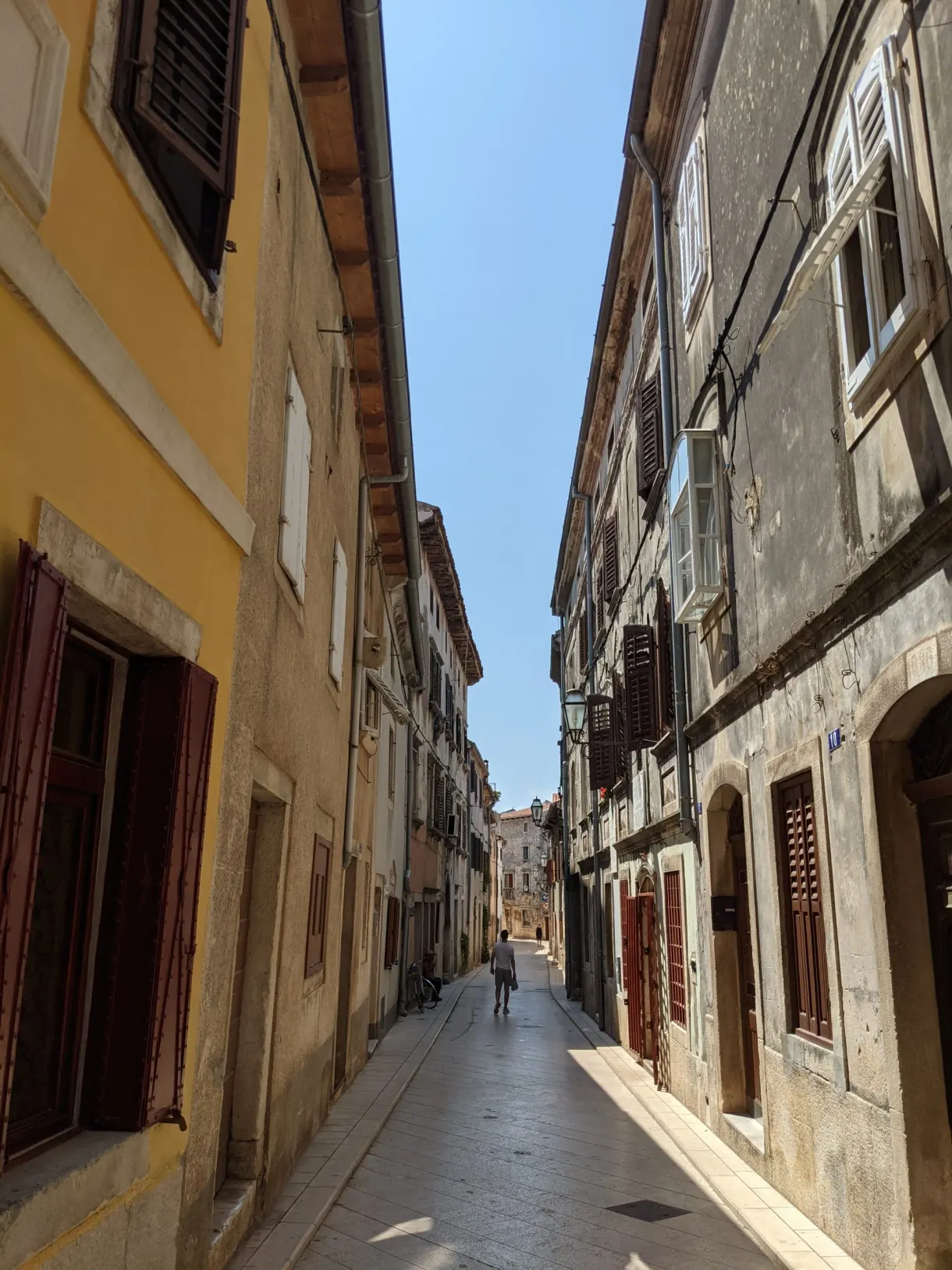 Narrow street between a yellow house and stone façades, Vodnjan