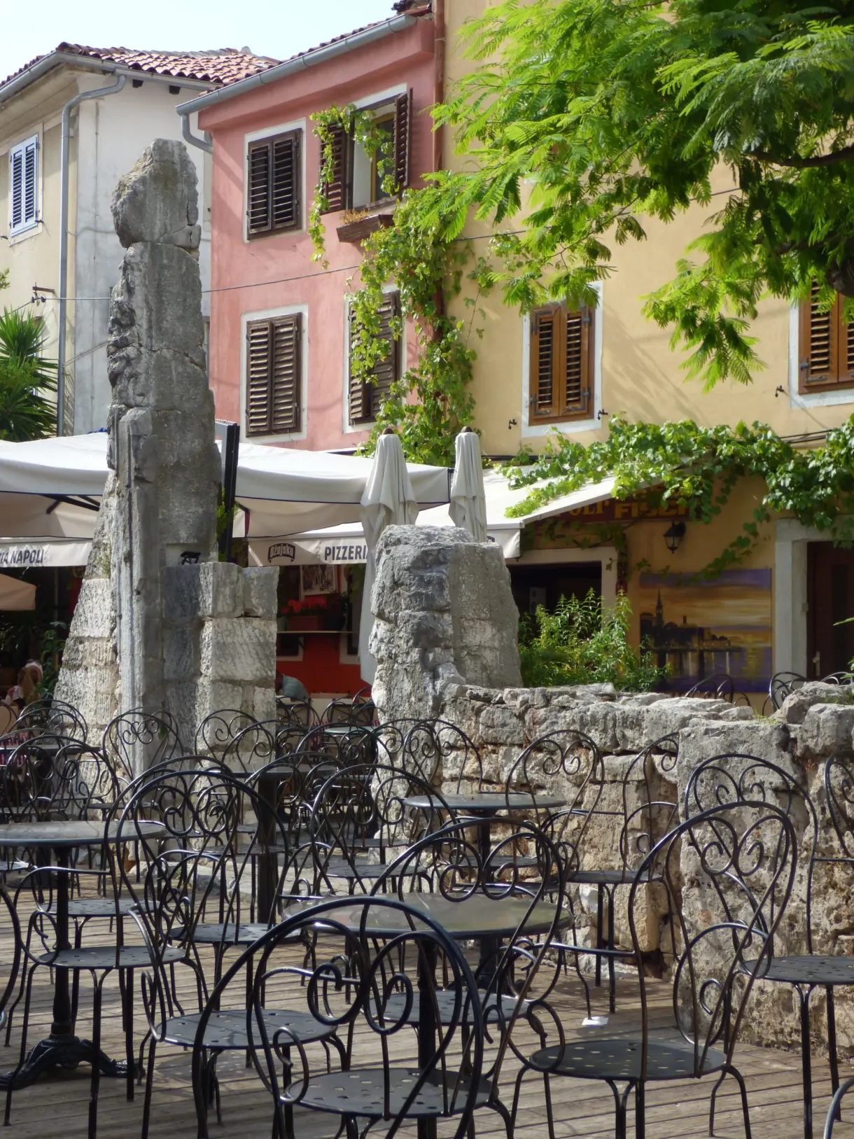 Wrought iron café chairs between ancient column shafts, Poreč