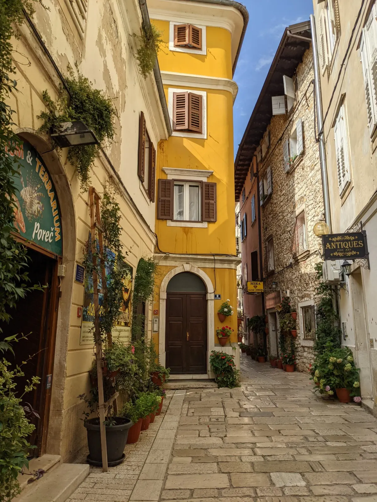 Shopping street in Poreč and its yellow house with brown shutters