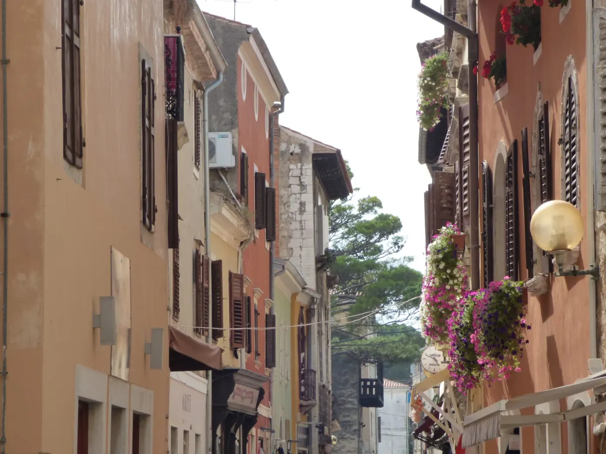 Pastel façades and hanging flower baskets in a street in Poreč