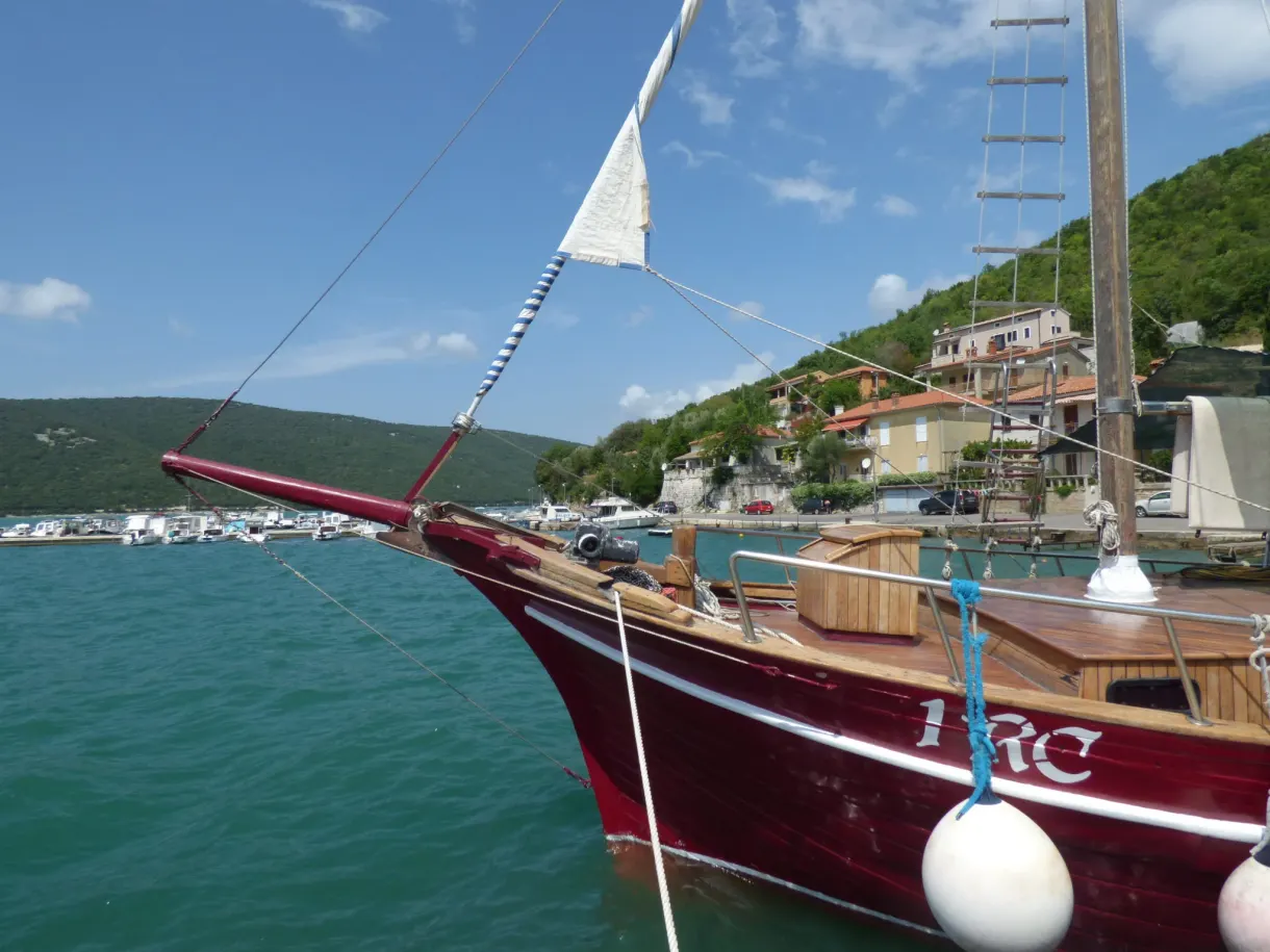 Bow of a burgundy sailing boat moored in the port of Trget