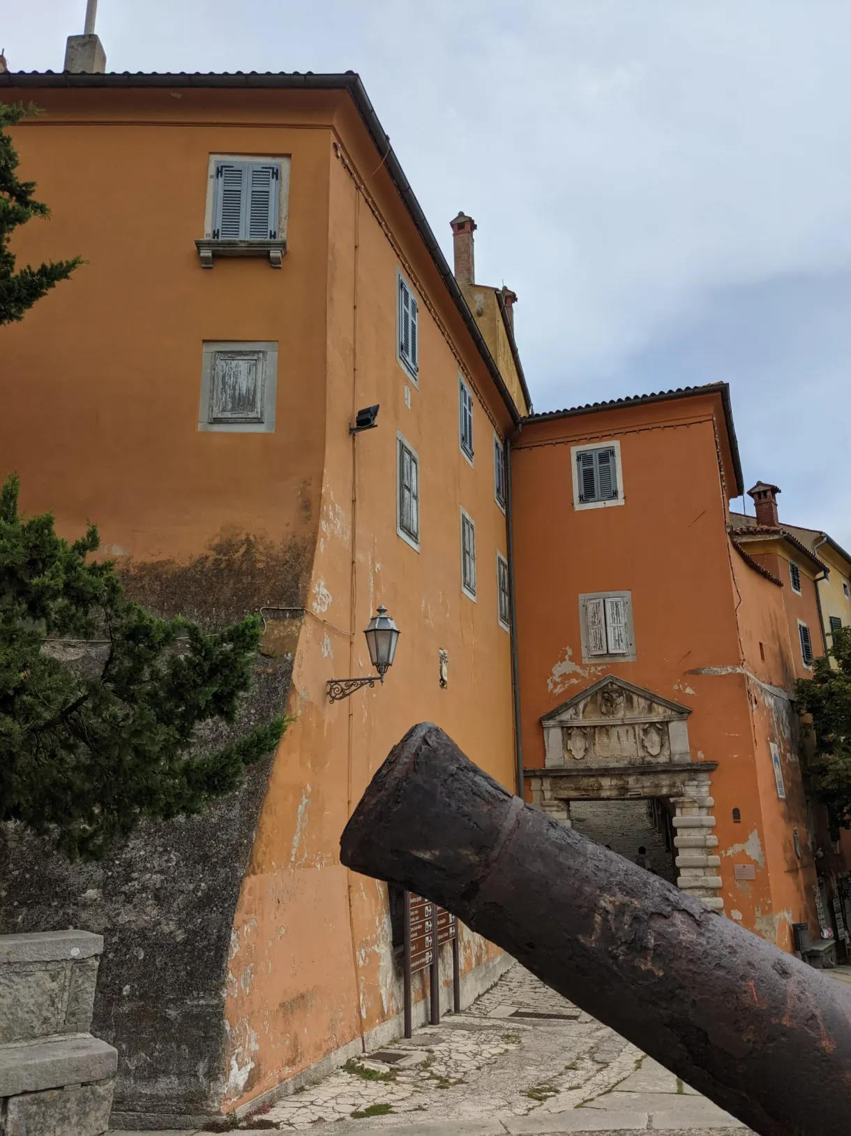 Cannon lying in front of an orange façade in the old town of Labin