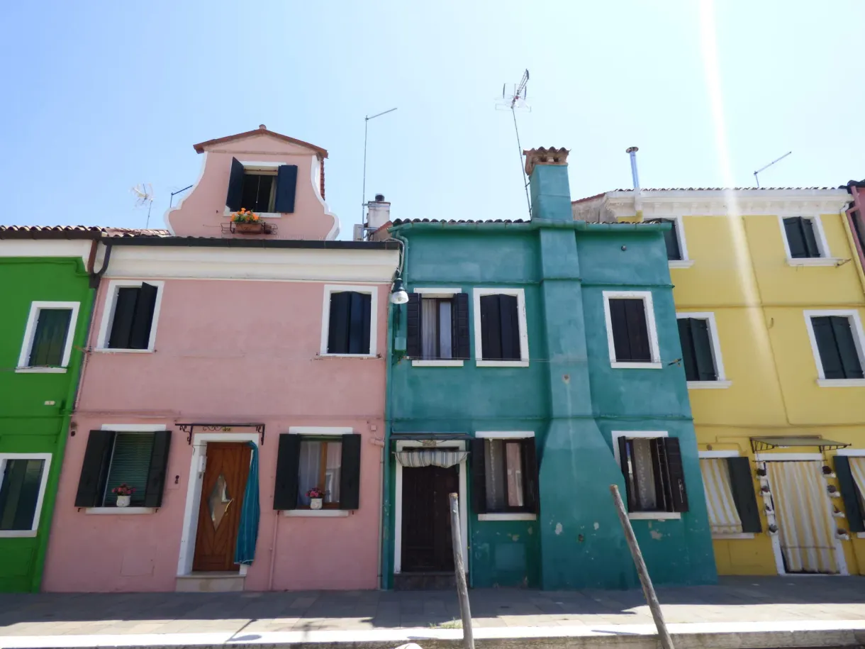 Façades rose, verte et jaune alignées sous un ciel bleu