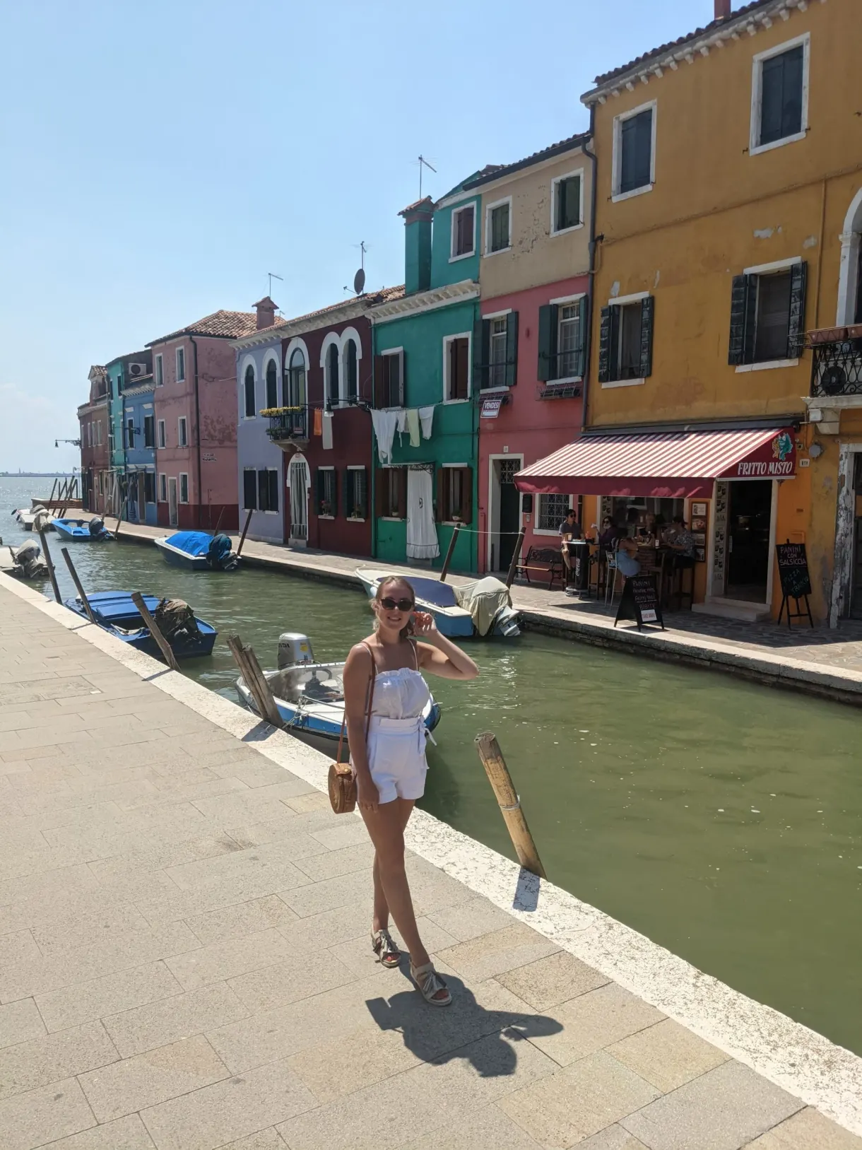 Promeneuse sur le quai devant les maisons colorées de Burano