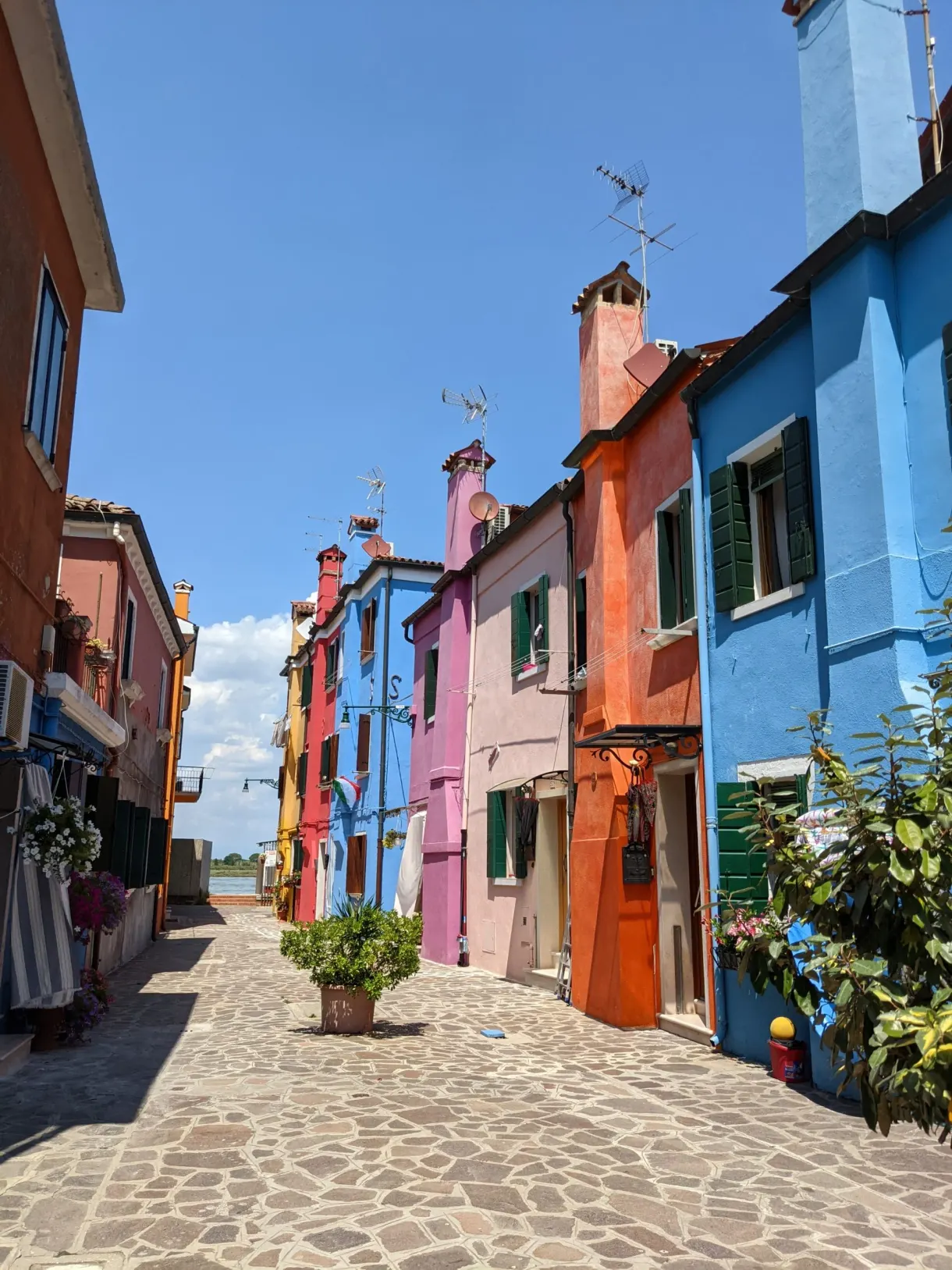 Ruelle pavée bordée de maisons bleues, roses et orange