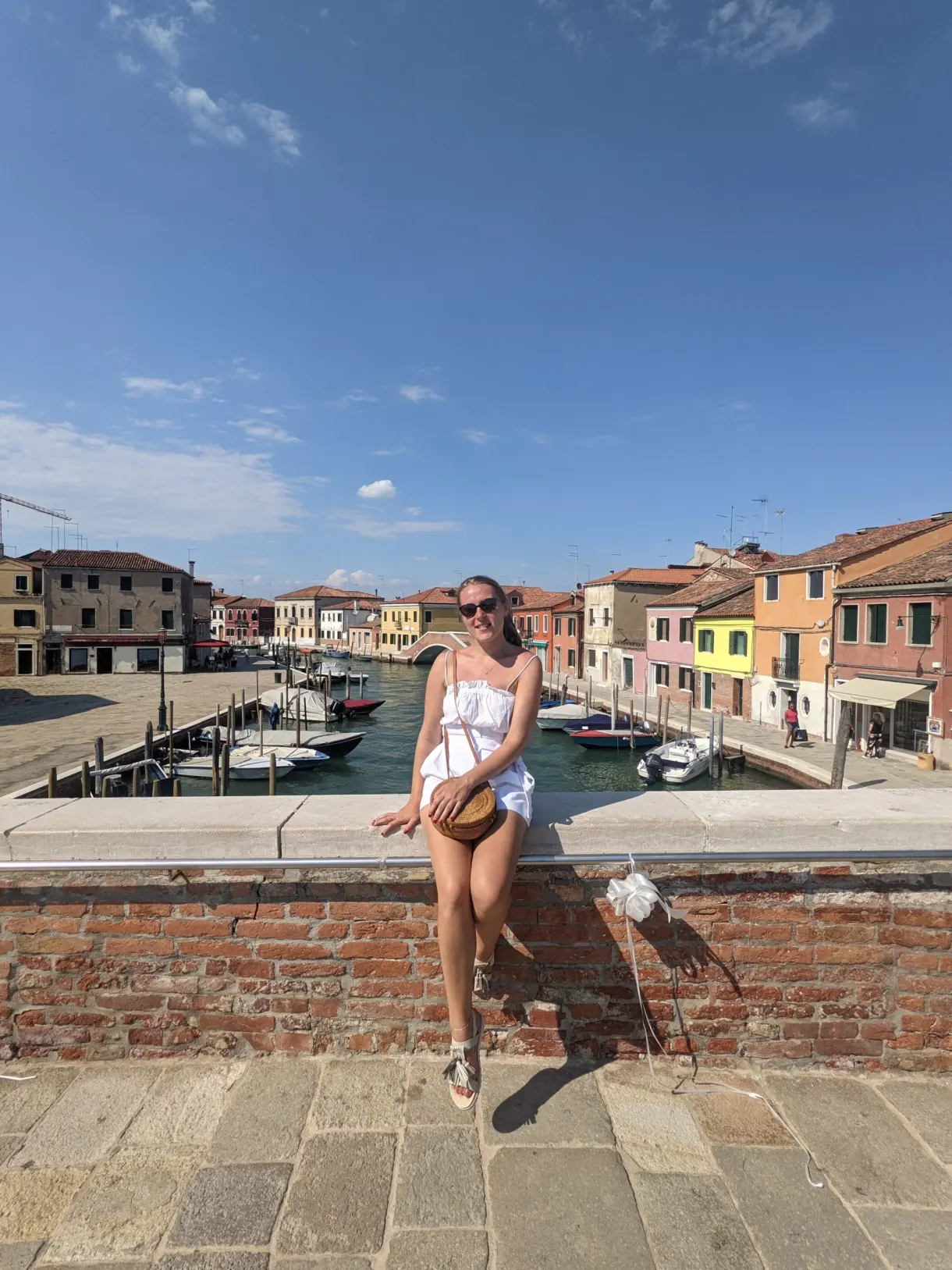 Assise sur un muret de brique au bord du canal