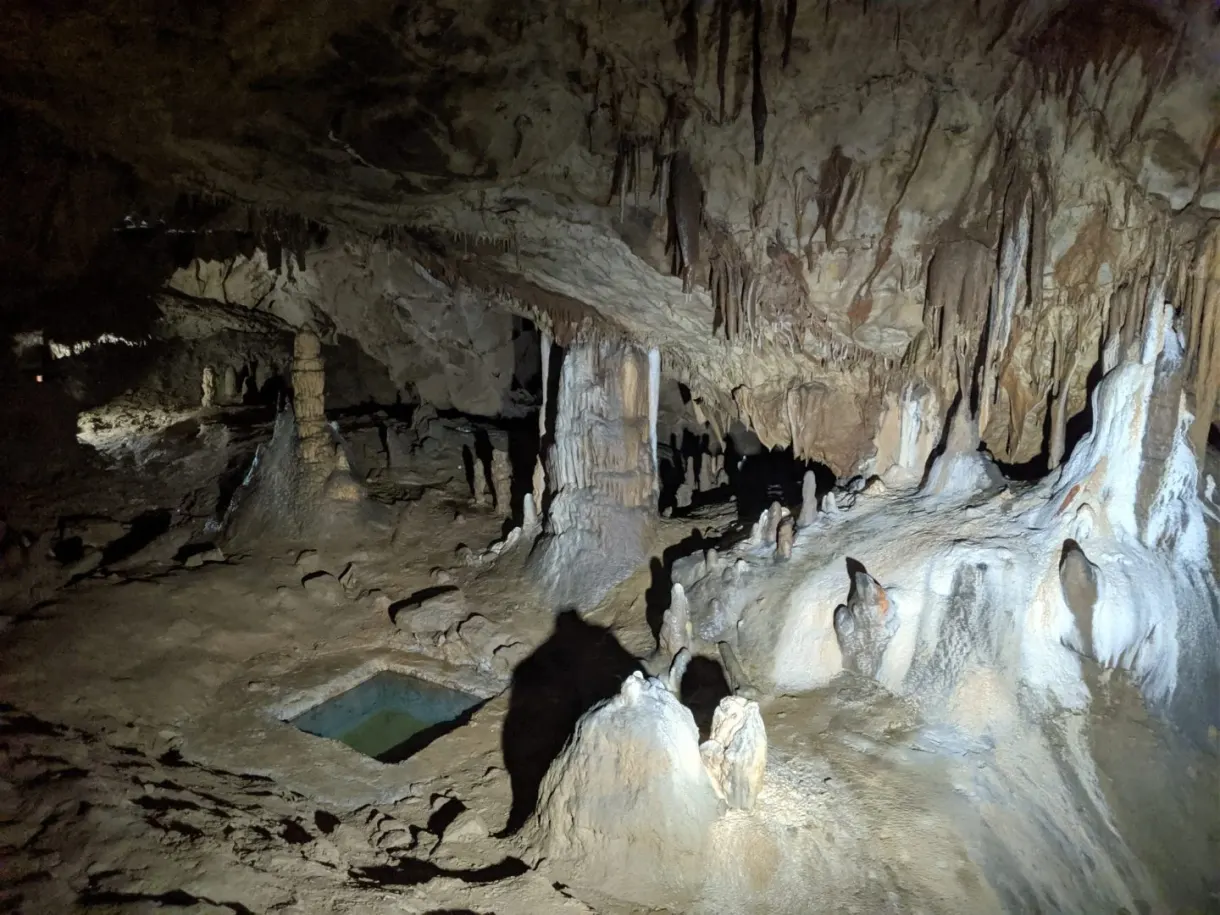 Salle hérissée de stalactites au-dessus d'un bassin vert