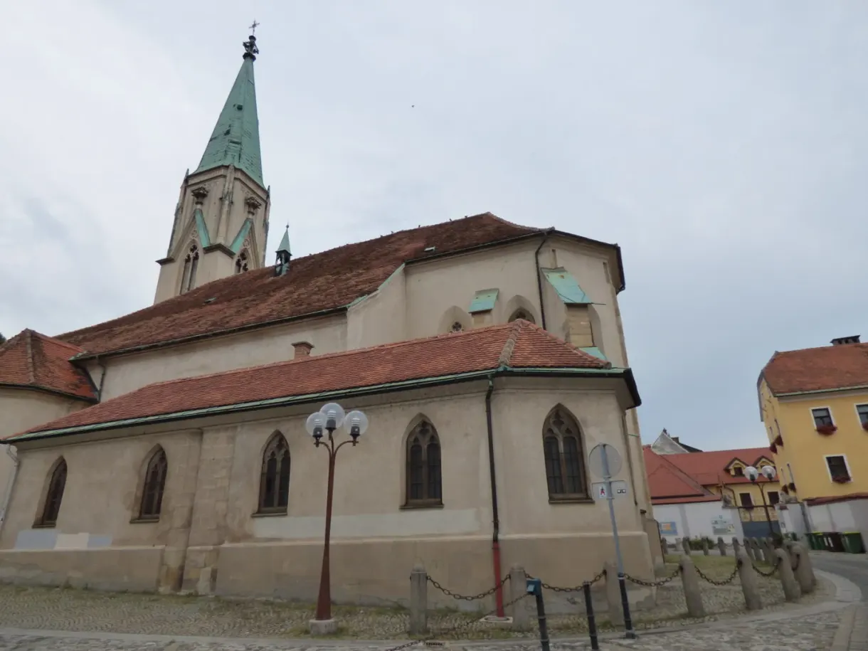 Gothic church with a pointed green spire at the roadside
