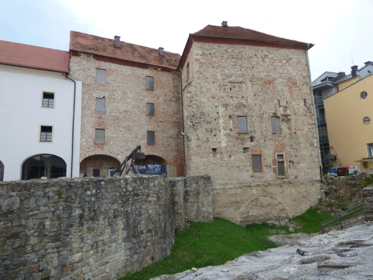 Massive ochre stone building standing above an old wall