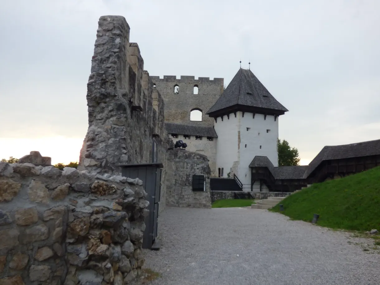 White tower with a pointed roof amid the ruins of the old castle