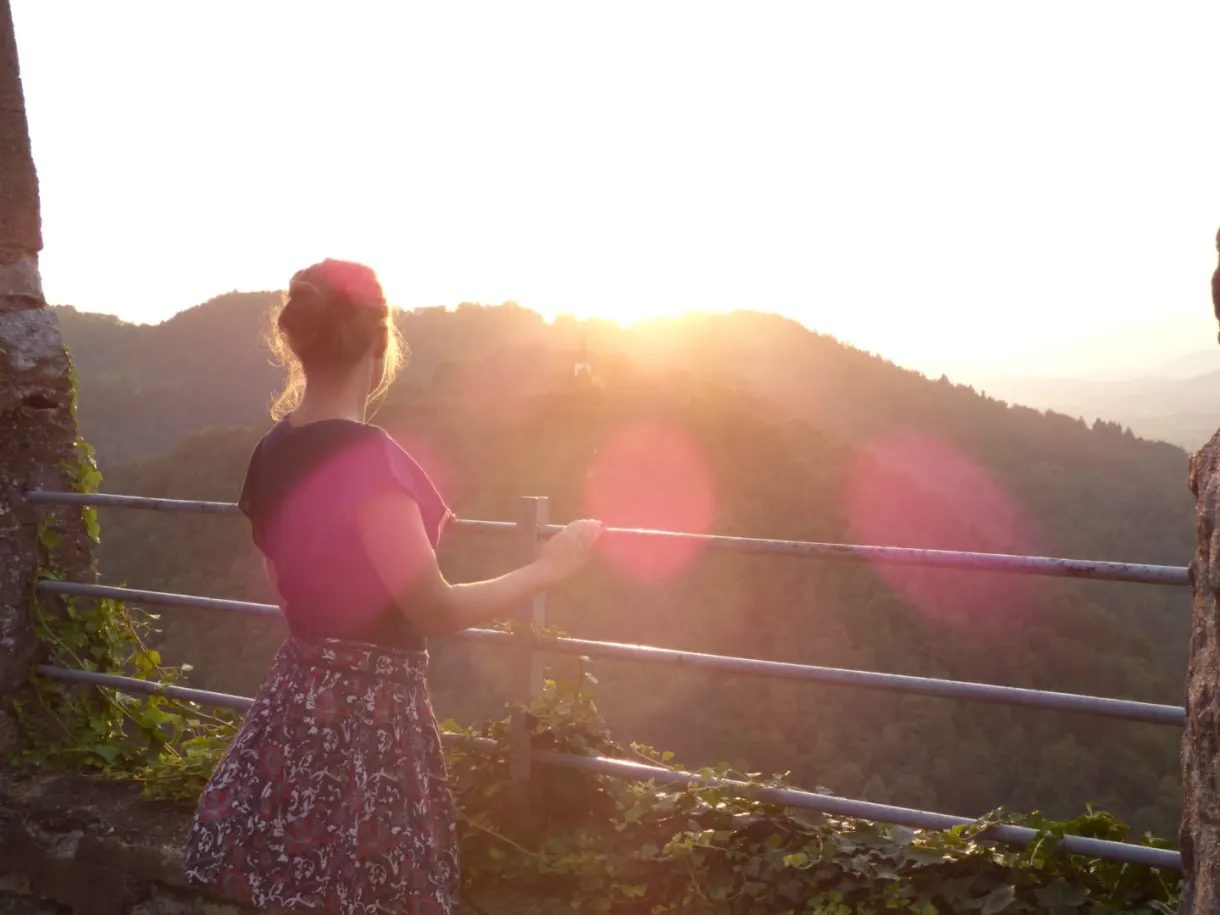 Woman against the light in front of the sun setting over the hills