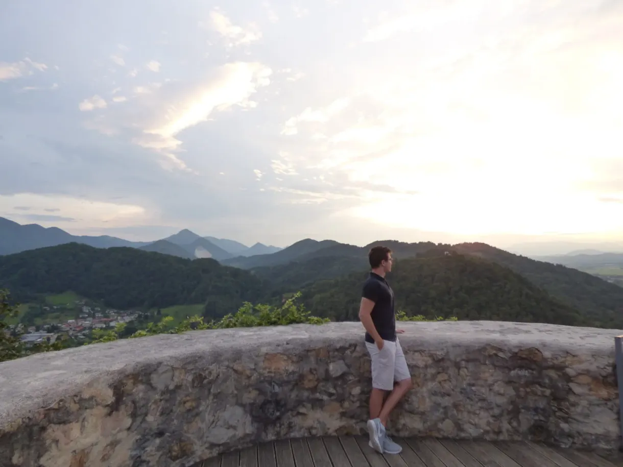 Man standing on the wooden terrace facing the wooded hills
