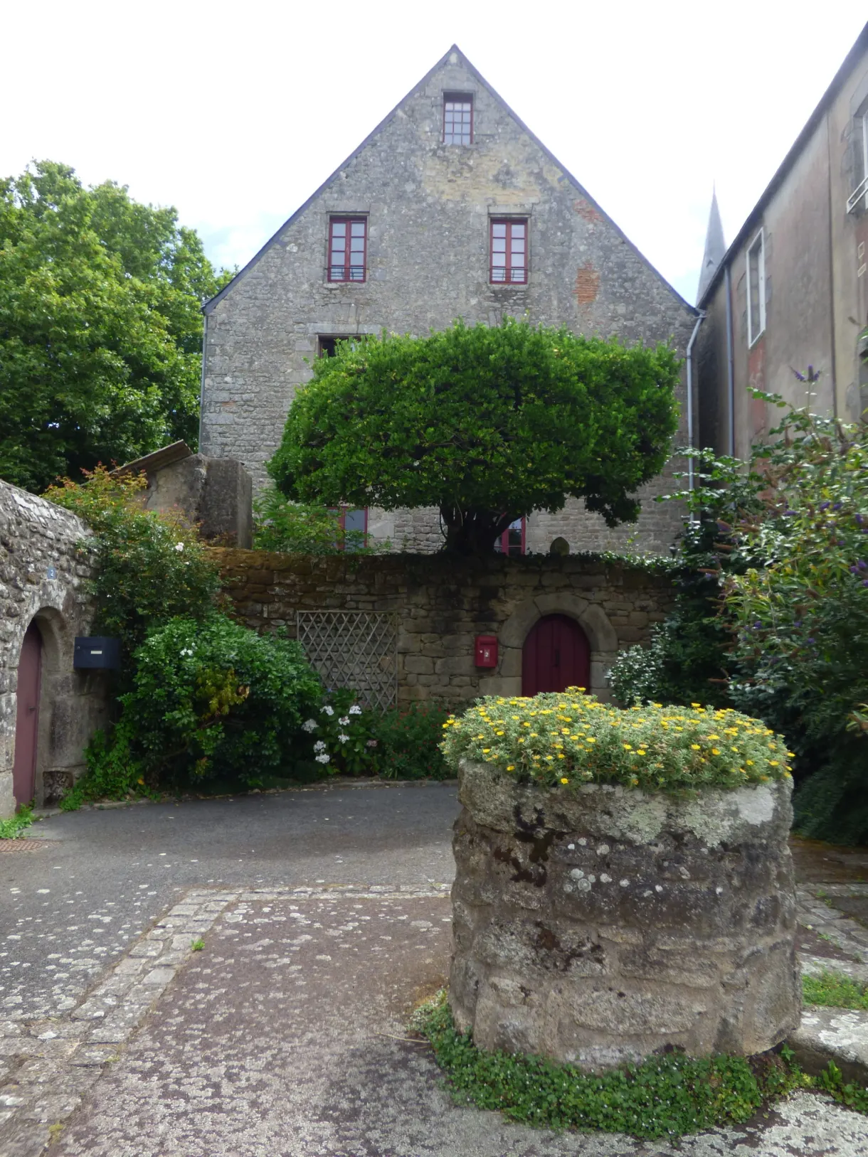 Old stone well in front of a house with a tall gable