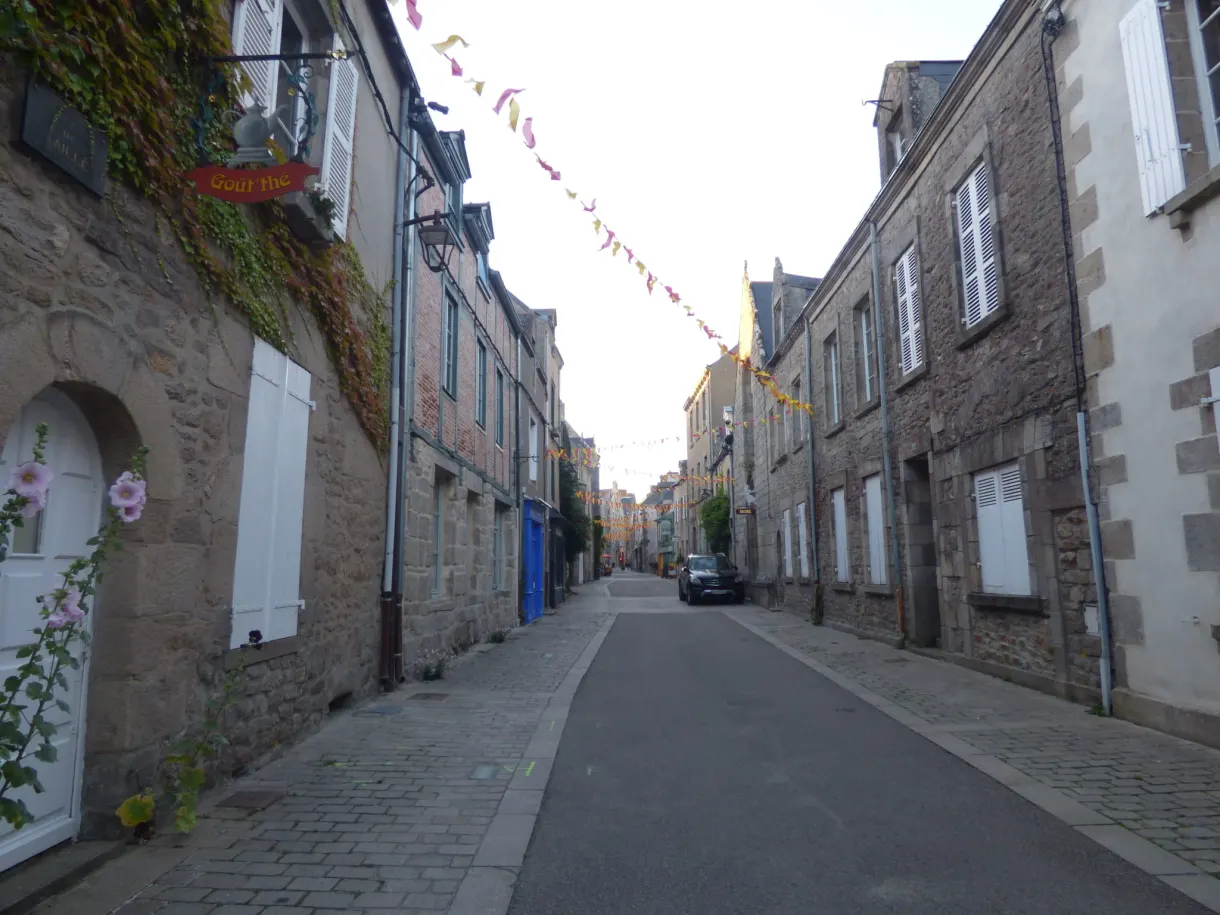 Empty shopping street decked with bunting between stone houses