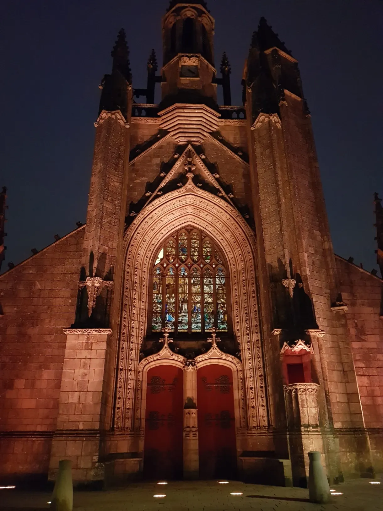 Facade and rose window of the collegiate church lit up in orange