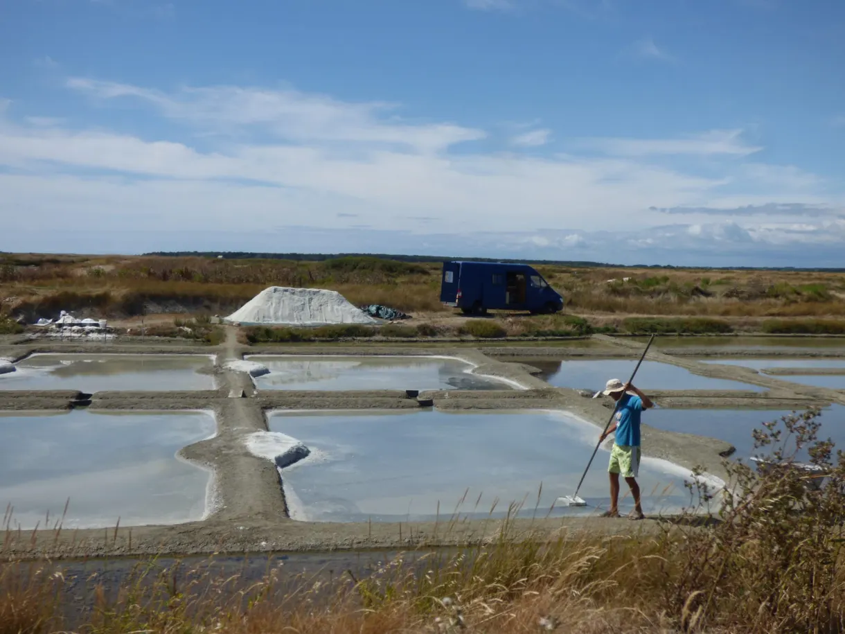 Salt worker drawing the salt with his las, blue van in the background