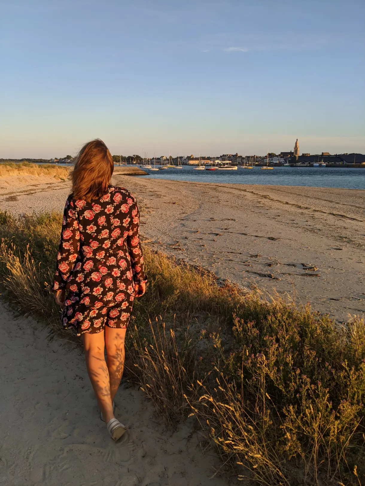Woman in a floral dress walking on a dune path