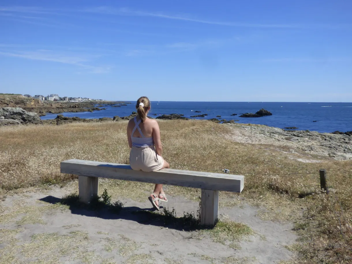 Woman sitting on a stone bench facing the open sea
