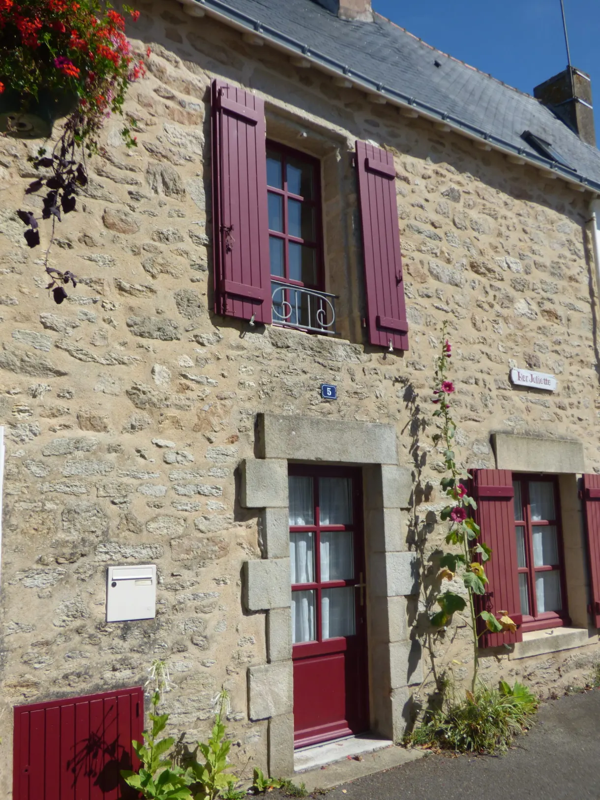 Granite house with red shutters and climbing plants