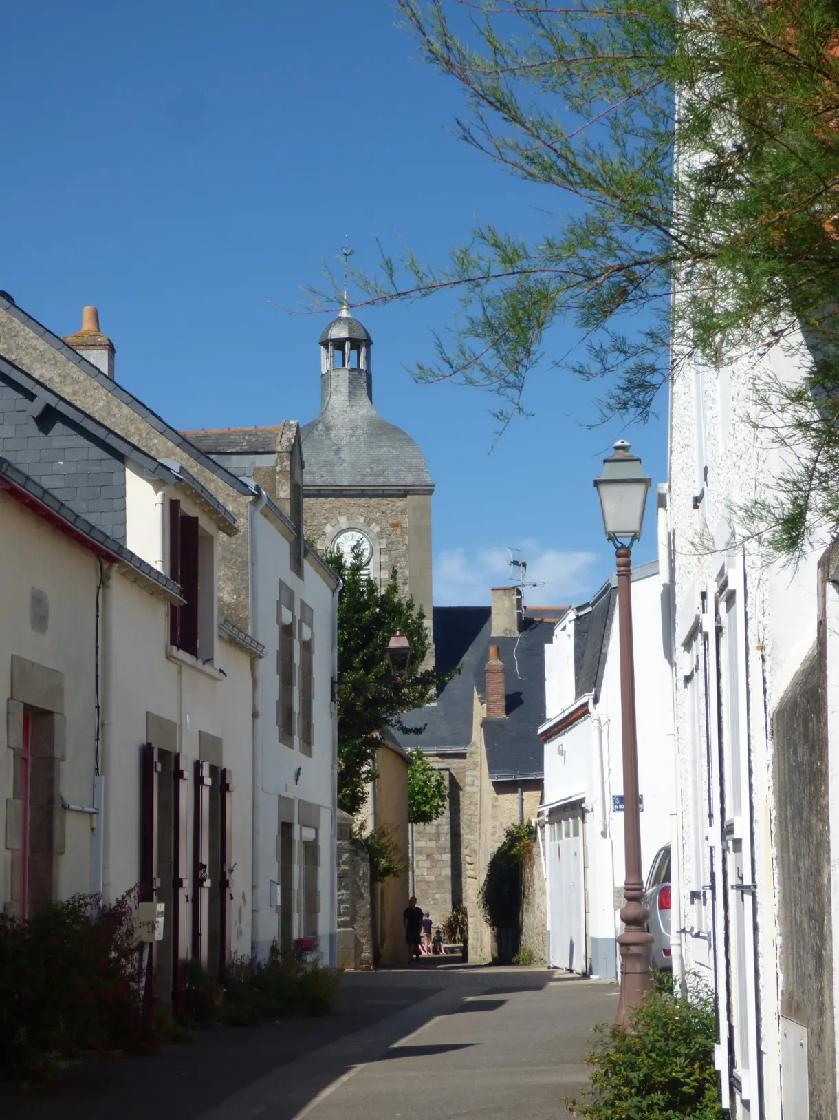 White lane leading towards a squat bell tower